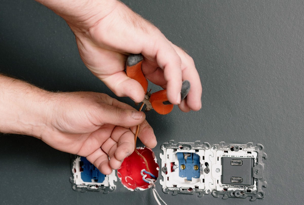Electrician using pliers on the wiring of a wall socket